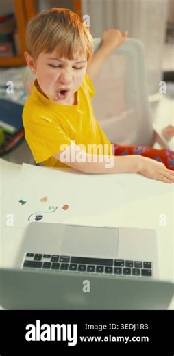 A child plays an online game at a desk in their home. The child shows strong emotions while focused on the computer. Colorful items are scattered around the desk Stock Video Footage - Alamy