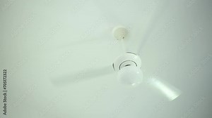 Close up white hanging ceiling fan with 3 blade and lamp spinning fast and cooling down the air in the room. Sultry summer heat without air condition at home