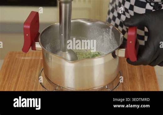 A chef using an immersion blender to puree boiled broccoli in a pot and combine it with cream while preparing a broccoli cream soup. The footage highlights smooth texture transformation, controlled hand movement, and the blending process in a modern Stock Video Footage - Alamy