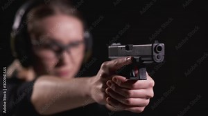 Young Blonde Female Aiming a Hand Gun in a Shooting Range with Ear and Eye Protection on in Slow Motion