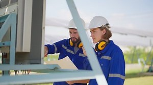 Maintenance engineer at solar farm trouble shooting looking at inverter control panel radio to team