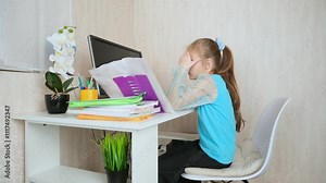 Little school girl sit at table at home write in exercise book prepare homework alone.