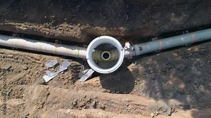 Concrete pipe tube installation. Aerial above men at work outside with heavy machinery to connect and install water or sewerage pipeline in a digging soil land Stock Video