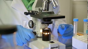 A doctor or scientist using a binocular microscope.