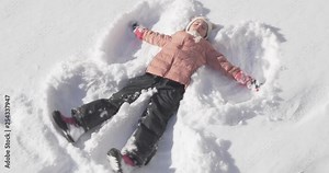 Beautiful little girl making a snow angel