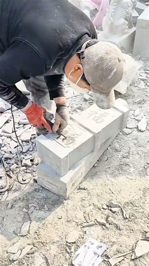 carving intricate chinese characters into gray stone blocks using specialized power tools and hammer