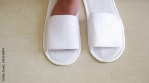 Closeup view of small cute legs of child wearing new white slippers in hotel room. Real time full hd video footage.
