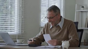 Old man using calculator to calculate personal finance, income, expenses for future plan. Concept of filing tax, tax deduction, tax payment and bill checking.