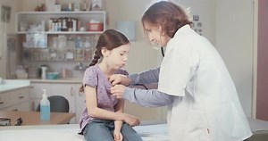 Doctor Examining Child with Stethoscope in Clinic