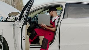 Automotive technician laptop conducts diagnostic tests inside vehicle auto service pinpoint car's malfunction. Auto service shop skilled mechanic using modern technology laptop to analyze car's issue.