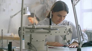 Tailoring of clothes. Seamstresses at work in workshop sewing clothes on sewing machine. Dressmakers sews clothes in atelier. Two women seamstress. Dressmaking in sewing business