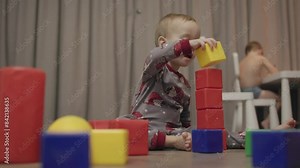 Young child toddler building blocks playing constructor learning educate. Toddler plays with blocks and bricks builds towers and buildings gain confidence Toddler playing blocks and bricks