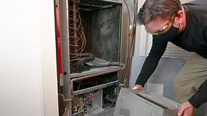 A professional hvac technician installs a blower fan motor on a older, commercial style heat pump.