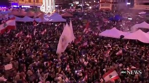 Protesters carry flags and flairs through the streets of Lebanon