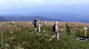 Hikers male and female trekking poles stop and charge their bodies with positive energy at a stone circle, Aerial orbit tracking drone shot