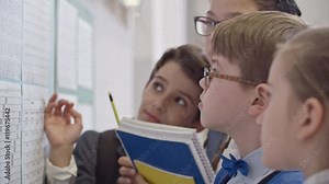 Concentrated and serious classmates studying new timetable and discussing lessons on first day of school after summer break