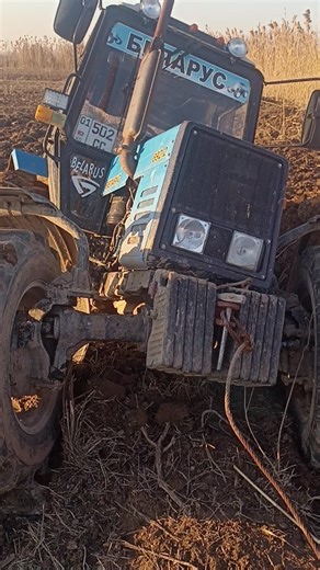 Blue Tractor Stuck in Muddy Field: A Farmer's Dilemma