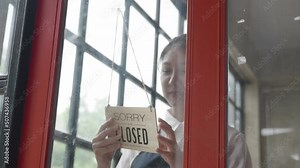 Business owner woman open sign on front door smiling welcoming clients to new shop.