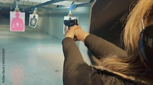 Woman shooting at a target with a pistol in a shooting range. Woman training to hit a target with a pistol. Training women police officers.