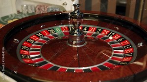 Casino: Roulette in Las Vegas with a white ball. The dealer croupier stops the roulette wheel and throws a game ball. The ball falls on the red field 34. Close-up. 4K video