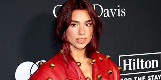 Dua Lipa Wears Eye-Catching Red Leather Trench Coat Covered With Gold Baubles