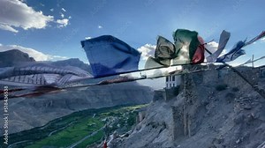 building of old traditional Tibetan Buddhist monastery with prayer flags in a stunning landscape view of a mountain valley in Himalayas