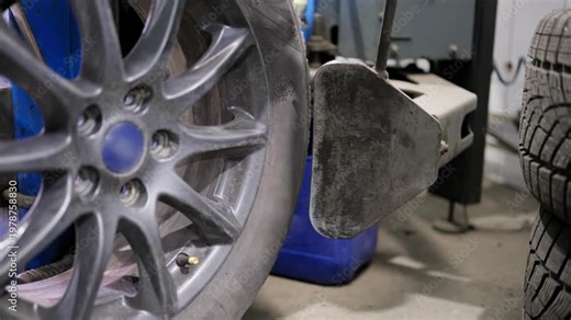 Close-up of a tire changing machine pressing the bead to separate it from the alloy rim during a seasonal replacement or flat repair procedure in a professional auto service garage