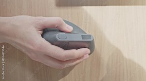 Closeup of woman hand using computer mouse on wooden desk surface. Concept of navigation and computer control