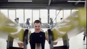 Concentrated man works on lever trainer for back muscle in spacious fitness club. Man promotes strength development and exercises for multiple muscle groups. Exercises on back muscles
