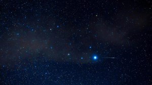 Starry sky with shining constellations and shooting stars at night. Timelapse of starry sky with clouds, nebulae and galaxies