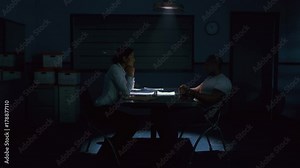 Criminal in handcuffs being interrogated by female police detective