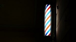 Barber pole spinning at night. International barbershop pole sign