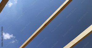 wooden beams used during the construction of the frame of the building, the manufacture of a new building using wood, against the blue sky