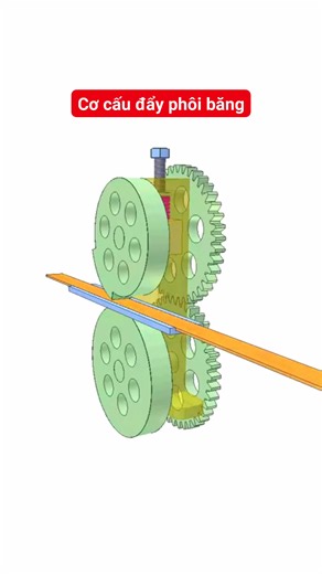 Tuyển tập cơ cấu mô phỏng kỳ thú ( Tiếp theo) Cơ cấu đẩy phôi băng.Khâu dẫn là trục dưới mang bánh răng và con lăn. Con lăn tiếp xúc với phôi băng màu cam qua lỗ hình chữ nhật của đường dẫn màu xanh. Trục trên mang bánh răng và con lăn. Con lăn trên bị làm nhỏ đường kính trên phần lớn chu vi. Ổ của trục trên có thể di chuyển theo phương thẳng đứng. Lò xo đỏ tạo lực ma sát ở chỗ tiếp xúc của băng với hai con lăn. Băng di chuyển gián đoạn theo chu kỳ do biển đổi đường kính ngoài của con lăn trên. 
