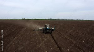 Tractor with Plough on Plowed. Ploughing and Soil Tillage. Agricultural Tractor on Cultivation Field for Sowing Seeds. Tractor During Field Cultivating. Planting and Seeding Equipment.