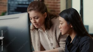 Team of software engineers talking about source code running on laptop screen while sitting at desk in it development office. Programmers collaborating on data coding group project.