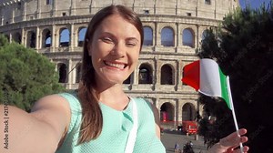 Woman doing selfie near famous attraction Colosseum in Rome, Italy. Teenage girl waving Italian flag in slow motion. Happy female tourist enjoying her european vacation. Student travel through Europe