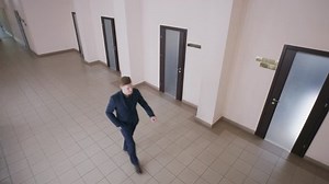Business people at office corridor. Successful man in elegant suit walks hallway and chats with client by phone. Female secretary with work papers comes out cabinet. Concept of CCTV. Security camera.