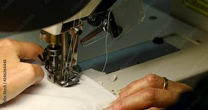 Woman sewing on sewing machine, sewing machine with two needles, fashion sewing workshop, white fabric, close-up