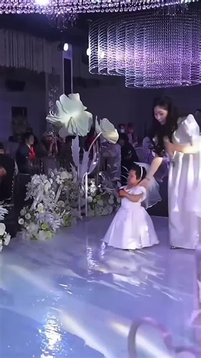 🇨🇳 一位年轻女性紧紧牵着女儿的手步入现场。她没有选择卑微的沉默，也没有激烈的对抗，而是以一种极其冷静且充满慈悲的力量，站在了曾经承诺共度一生的那个人面前。她每一步都走得异常沉稳，那是一种在巨大的心理落差中依然守护尊严的从容。她深知，此刻的歌唱不仅仅是告别，更是要在孩子幼小的心灵里，种下一颗关于勇敢与原谅的种子。 🇬🇧 A young woman steps forward, tightly holding her daughter's hand. She chooses neither humble silence nor fierce confrontation, but stands before the one who once promised a lifetime together with a remarkably calm and compassionate strength. Every step she takes is exceptionally steady, a composure that guards dignity even amidst a g