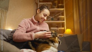 Portrait of young woman embracing her pet. Cute Welsh Corgi puppy resting with owner, spending time together at home. Concept friendship with dog and human, cute moments, relaxing, carefree