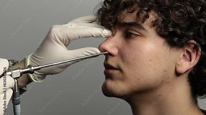 4k video Nose endoscopy. Rhinoscopy procedure with rhinoscope. ENT doctor otolaryngologist with headlight treat nose man patient.