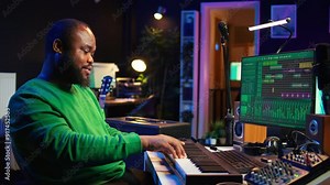 Modern producer playing piano keys to record new soundtrack, trying to produce song using midi controller electronic keyboard. Songwriter composer playing instrument notes to create tunes. Camera B.