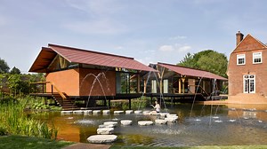 Stepping stones lead into house extension over an English lake by Hamish & Lyons