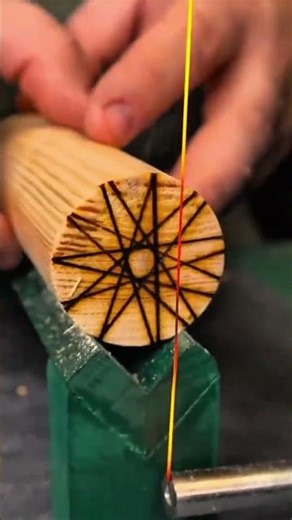Hands weaving geometric thread pattern on wooden rod