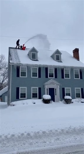 Homeowner clearing roof snow loses footing in sudden fall ERIE, PENNSYLVANIA — A residential security camera recorded a tense winter moment when a man using a snowblower to remove heavy accumulation from a large home’s roof slipped and fell from the structure. The footage shows the homeowner maneuvering the equipment near the roofline as built-up snow shifts toward the edge. Within seconds, the surface beneath him appears to give way, and he slides down the slope before falling off the roof into