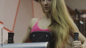 Very beautiful female trainer trains on a fitness machine in a fitness club