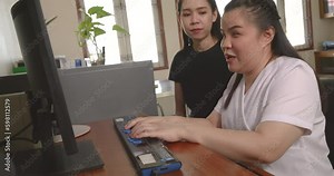 Happy Asian women co-workers in office workplace including person with blindness disability using computer with refreshable braille display assistive device. Disability inclusion at work concepts.