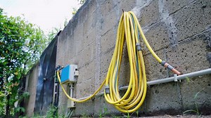 Installed water faucets with timer box for irrigation system, yellow pipes attached to outdoor tap ready for irrigation garden or industrial field according to the set timer, water irrigation in