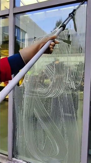 Cleaning large glass window with sweeping foam strokes